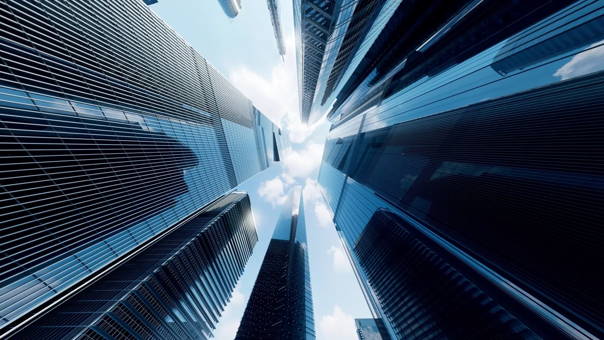 Glass skyscrapers rising into a bright sky